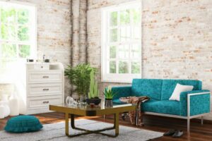 living room with blue green couch, brick walls, coffee table, and white dresser