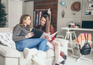 Two women talking and lounging on couch in apartment