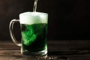 Green beer in stein with more beer being poured into it