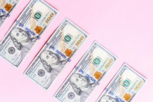 100 dollar bills on pink background