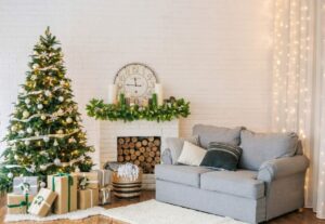 Living room with christmas tree, presents, fireplace, and a grey couch