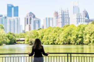 Woman standing on balcony overlooking Piedmont Parka and Atlanta skyline