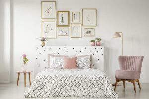 Tidy bedroom with polka dot comforter, pictures on wall and side table and chair