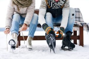 two people sitting on bench putting on ice skates