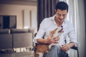 man sitting in chair at home with corgi on his lap