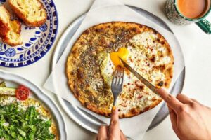 person cutting pizza with a fork and knife