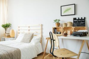 white bedroom with bed, desk, chair, and wall picture