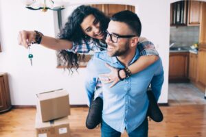 young couple holding keys in new apartment on move-in day