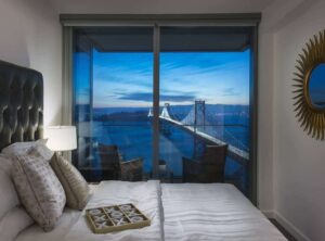 window with view of bay bridge and bed in view