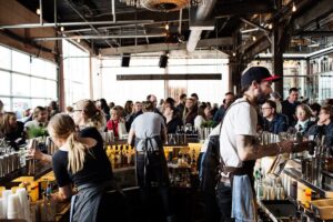 picture of people behind bar serving drinks to large crowd