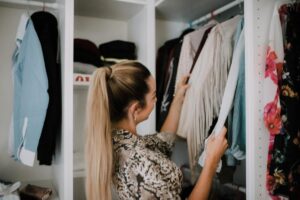 young woman sorting through clothes in closet
