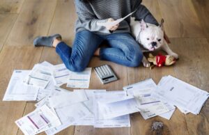 woman on floor with dog looking over bills