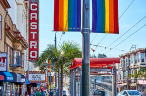 castro sign with rainbow flag next to it and blue skies