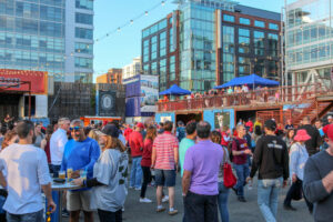 people outside drinking and eating under string lights