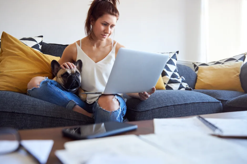 woman on couch holding a laptop and a dog in one of the top pet friendly apartments in Houston, TX