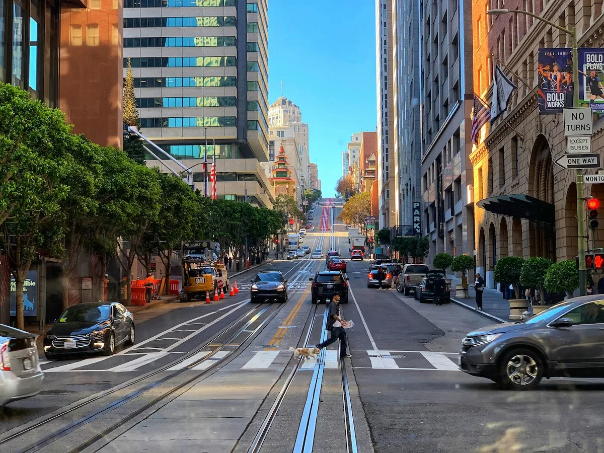 Downtown San Francisco street with cars, cable-car rails, and high-rise buildings โ representing the cityโs urban rental core and cost-of-living environment for renters in 2025.