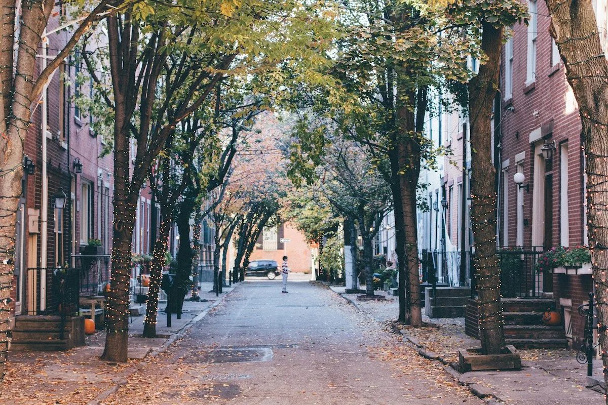 Tree-lined residential street in Philadelphia with classic rowhomes and fall leaves, representing the cityโs walkable neighborhoods and community atmosphere for renters.