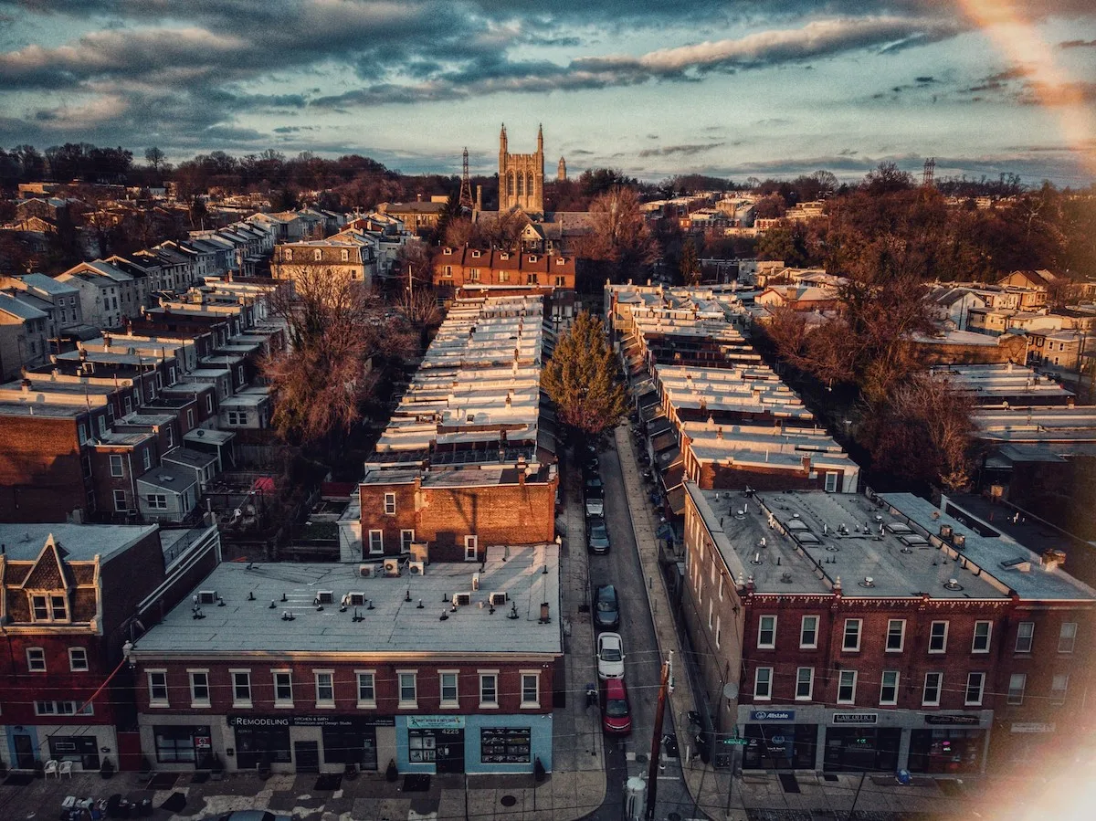 Aerial view of a Philadelphia neighborhood with rows of brick rowhouses and a church in the distance, highlighting the cityโs historic architecture and dense housing landscape for renters in 2025.