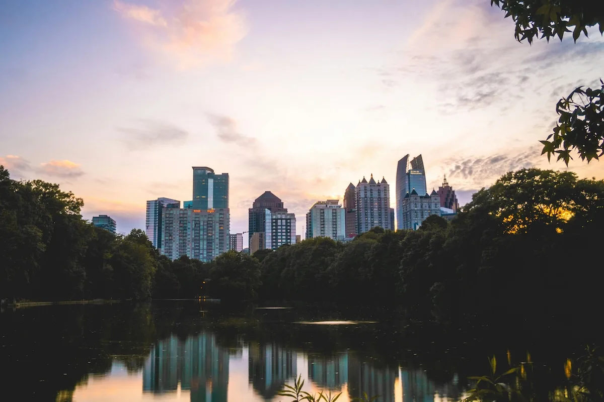 Atlanta skyline at sundown with trees and a lake, representing the city served by the top 6 Atlanta moving companies