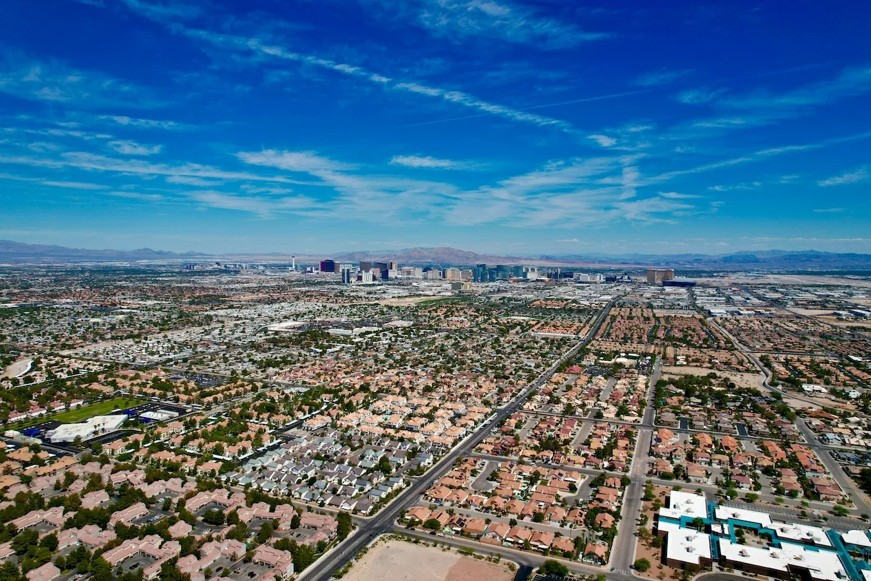 Aerial view of suburban Las Vegas neighborhood with single-family homes and desert mountains in background showing affordable housing options.