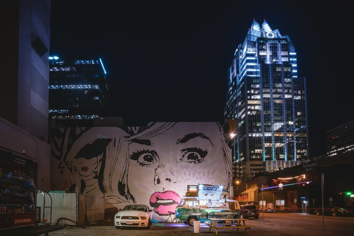 Night view of downtown Austin with a street mural, representing the city neighborhoods where renters look for lower-cost apartments.