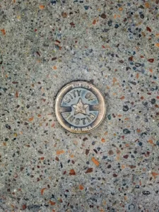 City of Austin survey marker embedded in a sidewalk, symbolizing local neighborhoods analyzed for affordable rent prices.