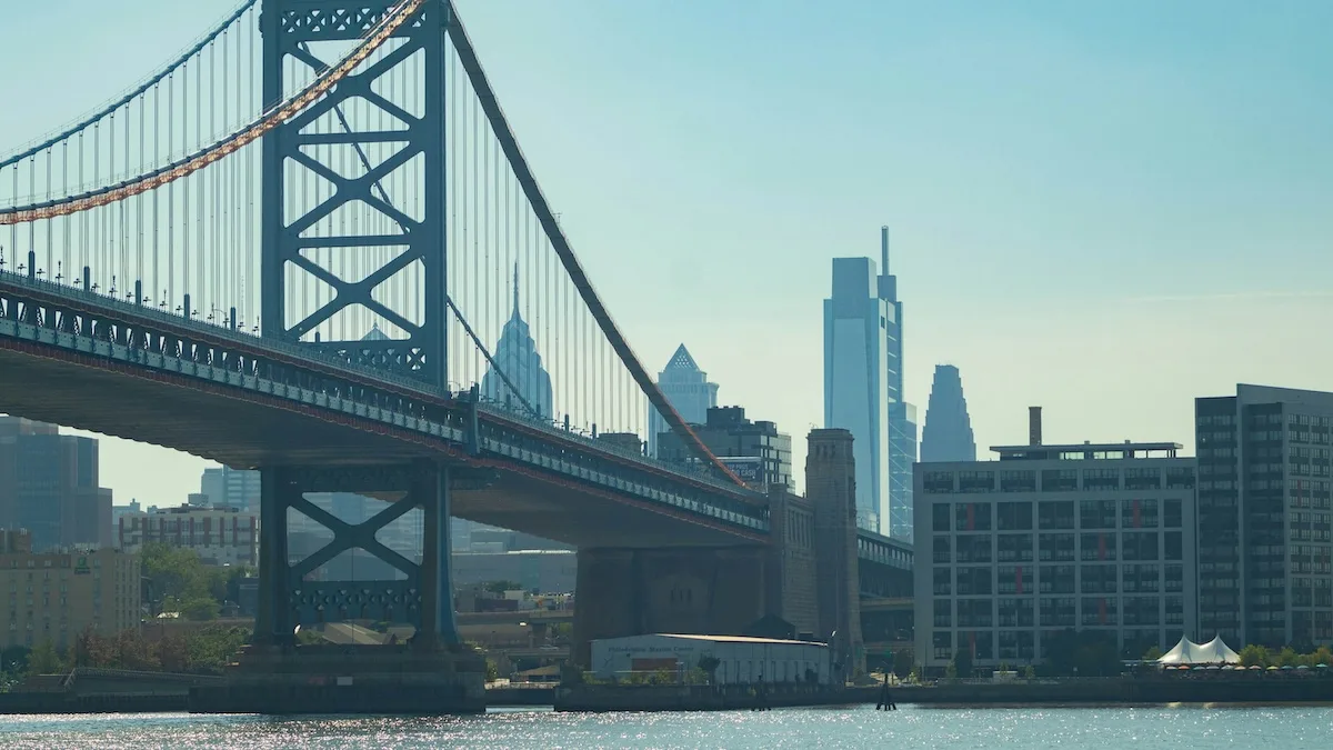 View of Center City Philadelphia skyline and Ben Franklin Bridge from Camden, New Jersey across the Delaware River, showing the transit connection between Philadelphia and nearby New Jersey suburbs