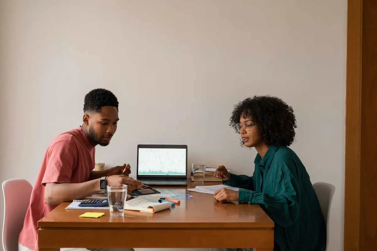 Two renters reviewing their budget and calculating how much rent they can afford using a laptop and calculator